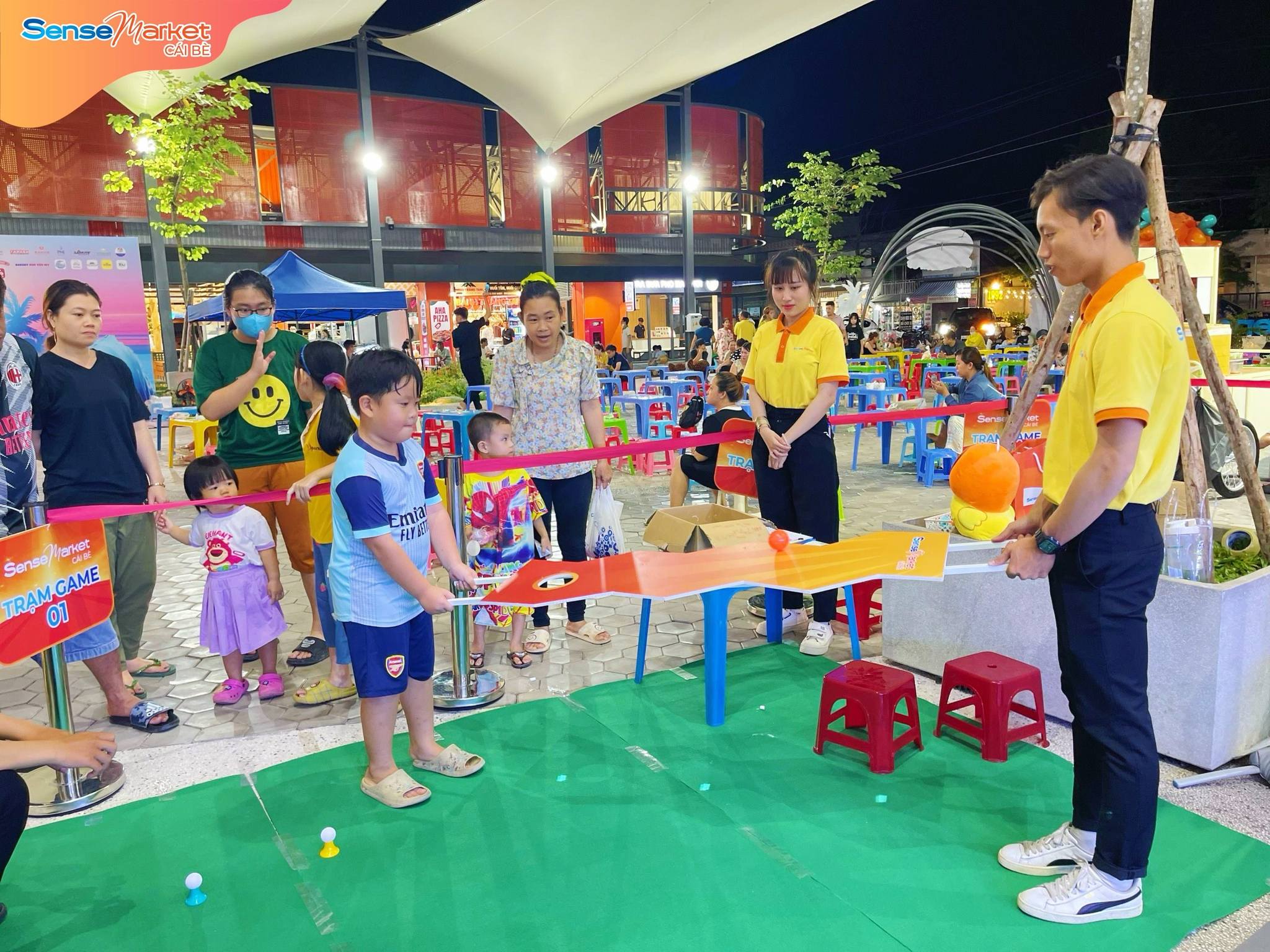 Nhân viên SMCB đang hướng dẫn khách hàng chơi Trạm game của chương trình "Đón hè rực rỡ - Săn quà hết cỡ"