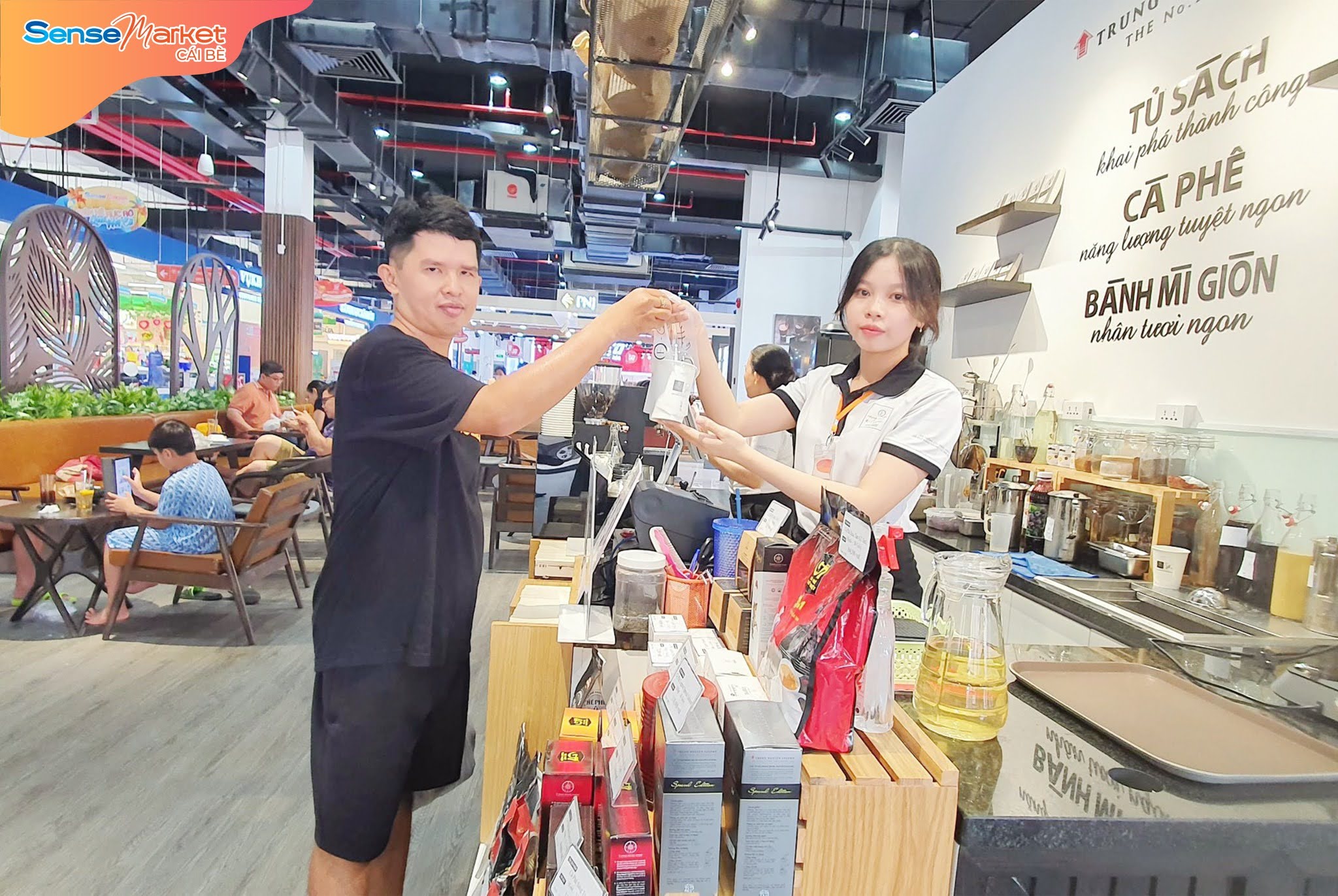 Khách hàng nhận đồ uống từ nhân viên tại quầy cà phê trong SenseMarket Cái Bè