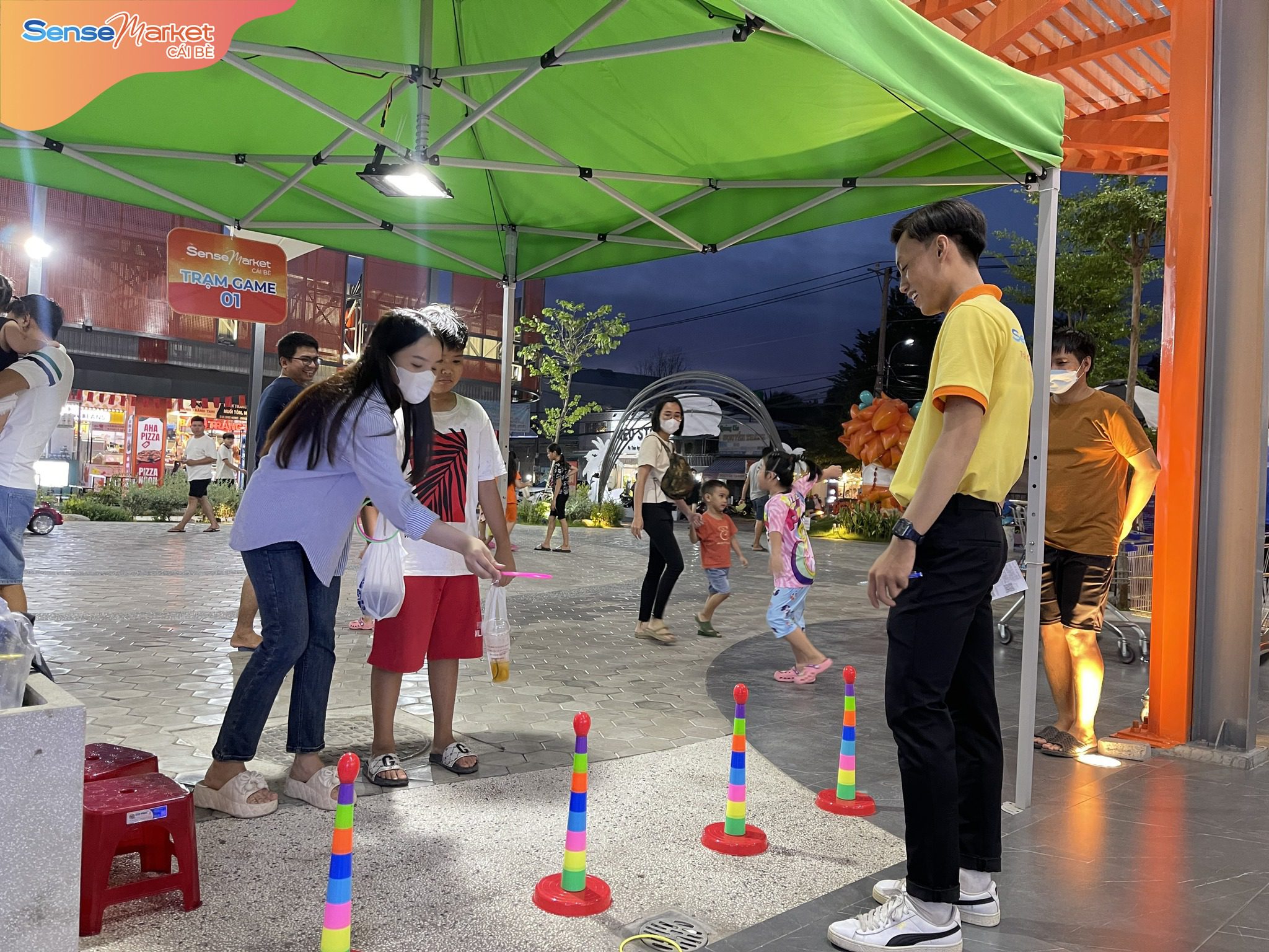 Nhân viên SMCB đang hướng dẫn khách hàng chơi Trạm game của chương trình "Đón hè rực rỡ - Săn quà hết cỡ"